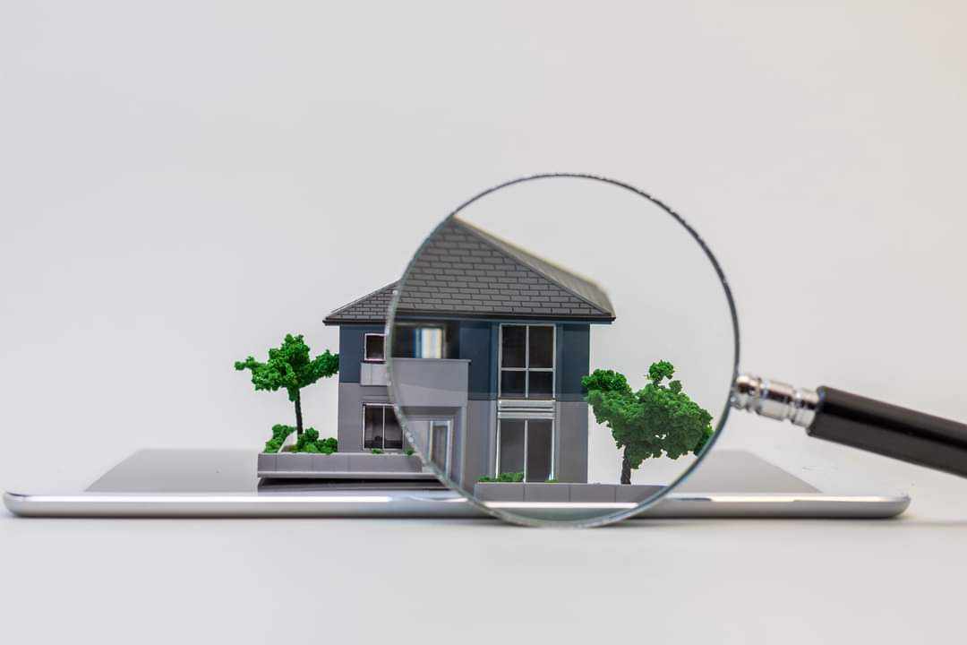 A mini house sitting on an iPad, under a magnifying glass